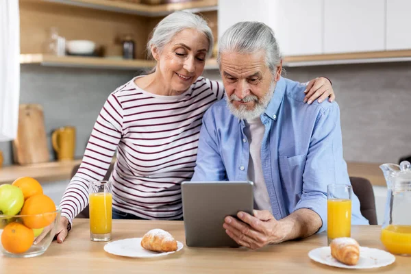 Happy Senior Couple Browsing Internet Digital Tablet Breakfast Kitchen Smiling — Stockfoto