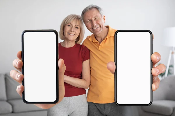 Happy Senior Couple Standing Home Showing Big Blank Smartphones White — Stok fotoğraf