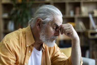 Side view of sad bearded elderly man touching his nose bridge, experiencing financial hangover while crisis 2022, closeup shot, copy space. Financial topics and resources for seniors
