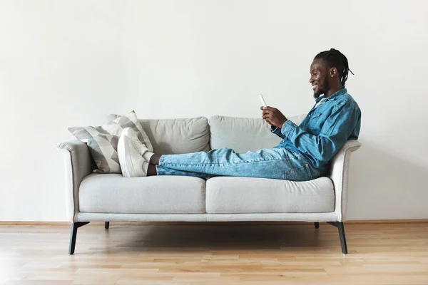 Cheerful Black Man Using Mobile Phone Texting Networking Sitting Sofa — Foto de Stock