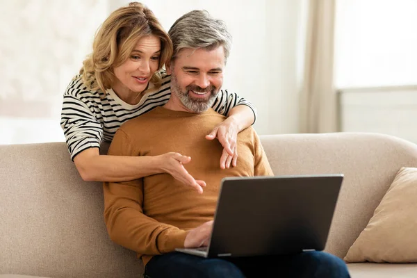 Wife Hugging Husband While Working Online Laptop Computer Sitting Sofa — Stock fotografie