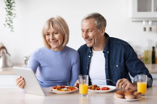 Happy Senior Couple Using Digital Tablet While Having Breakfast Kitchen — Stockfoto