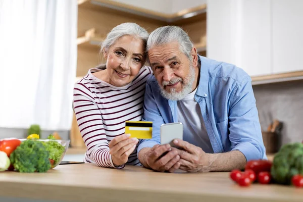 Portrait Happy Senior Spouses Smartphone Credit Card Kitchen Smiling Married — Stockfoto