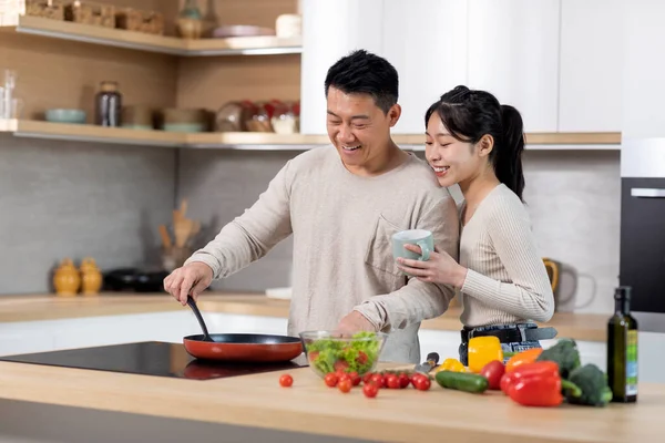 Happy Attractive Young Chinese Lady Supporting Her Husband While Cooking — Photo