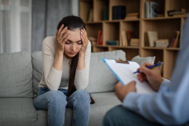 Despaired sad young caucasian lady suffering from mental problems listens to male doctor in office clinic interior. Prescription for depression treatment, medicine support, session with professional