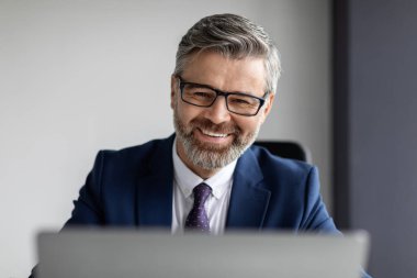 Closeup Portrait Of Handsome Bearded Middle Aged Businessman Wearing Eyeglasses Working With Laptop In Office, Smiling Happy Male Entrepreneur In Suit Using Computer At Workplace, Copy Space
