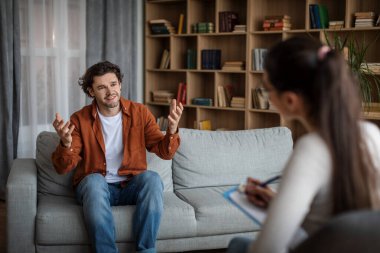 Smiling emotional young caucasian man patient speaks with doctor psychologist in office clinic interior. Psychological therapy, personal consultation, treatment of mental problems and medical support