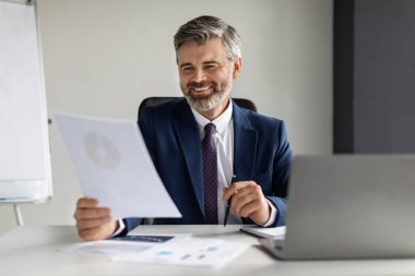 Smiling Middle Aged Businessman Working With Papers At Desk In Office, Successful Mature Entrepreneur Reading Financial Reports And Smiling, Enjoying Company Growth, Closeup Shot, Copy Space