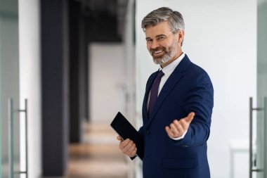 Handsome Middle Aged Businessman In Suit Making Inviting Gesture, Welcoming To Enter Office, Friendly Mature Male Entrepreneur With Digital Tablet In Hands Standing Near Open Door, Copy Space