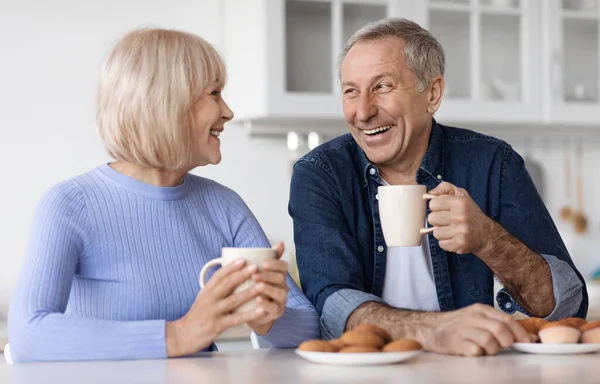 Positive Beautiful Elderly Spouses Drinking Tea Pastry Home Sitting Kitchen — Foto de Stock