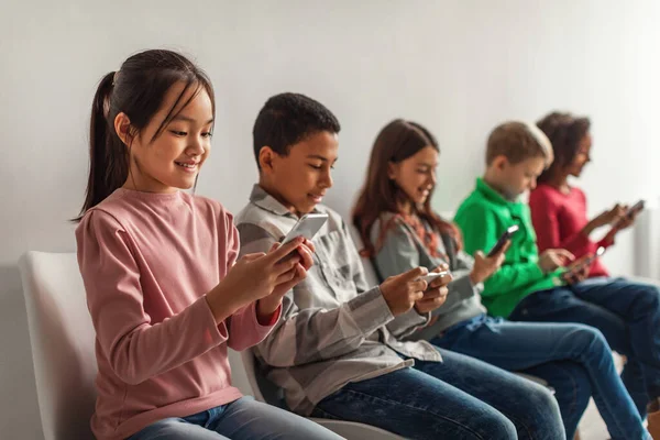 Multiethnic School Kids Using Mobile Phones Playing Online Games Browsing — стоковое фото