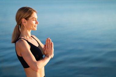 Namaste. Relaxed Beautiful Middle Aged Woman Meditating Outdoors Near River, Calm Blonde Female Practicing Yoga, Standing With Clasped Hands And Eyes Closed, Enjoying Healthy Lifestyle, Copy Space