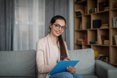 Smiling glad young european female doctor psychologist in glasses in office interior. Medical support, psychological therapy, session with professional, help and new normal during covid-19 pandemic