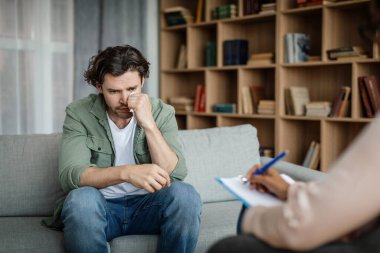Despaired millennial european man client cry at meeting with black woman psychologist in office clinic interior. Psychological therapy, session with doctor, mental help, facial expression and emotions