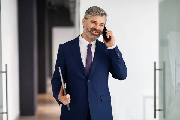 Smiling Middle Aged Businessman Talking Cellphone While Walking Out Office — стоковое фото