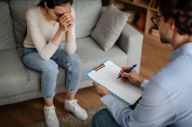 Serious millennial caucasian male psychologist listen to crying female patient in clinic interior, cropped. Professional medical care, patient care, depression treatment, prescription and support