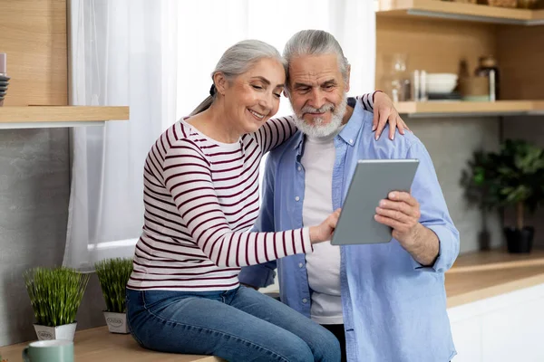 Happy Senior Spouses Using Digital Tablet While Relaxing Kitchen Together — Stok fotoğraf