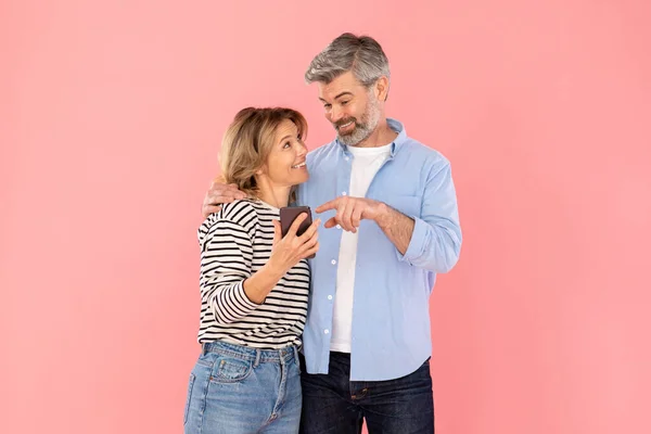 Middle Aged Married Couple Using Cellphone Pointing Finger Recommending Mobile — Stockfoto
