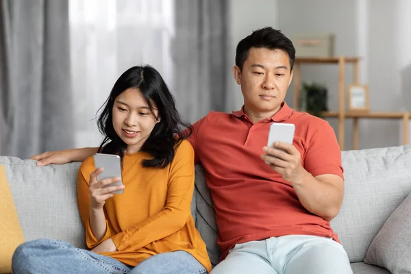 Asian Couple Sitting Couch Together Using Smartphones Dont Talk Each — Foto de Stock