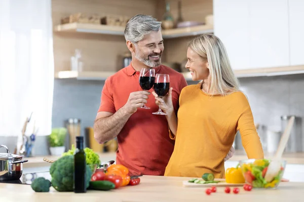 Happy Middle Aged Couple Drinking Red Wine While Cooking Man — Stock fotografie