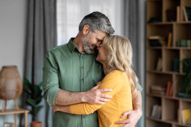 Mature Romance. Portrait Of Romantic Middle Aged Spouses Bonding At Home, Loving Man And Woman Embracing And Touching Foreheads While Standing In Living Room, Enjoying Their Happy Marriage
