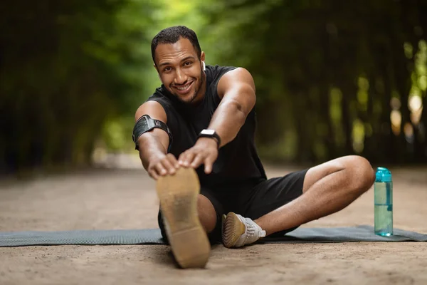 Positive Handsome Muscular Millennial Black Man Stretching Public Park Sitting — Stockfoto