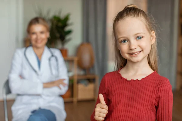 Щаслива Маленька Дівчинка Педіатричній Клініці Лікарем Фоні Посміхається Камеру Показує — стокове фото