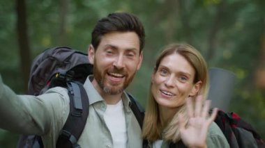 Tourist online diary. Camera pov portrait of happy man explorer with backpack recording video blog on phone, woman showing thumb up gesture, recommending active hobby in forest, slow motion