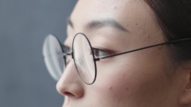 Corporate work and eyesight problems. Close up portrait of professional asian woman office manager in eyeglasses looking aside at empty space, slow motion
