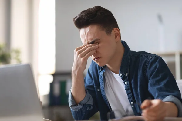 Portrait Tired Millennial Guy Suffering Eye Strain While Using Laptop — стоковое фото