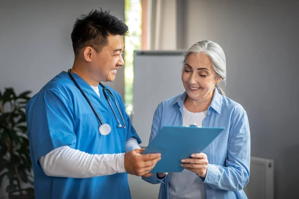 Smiling Middle Aged Chinese Male Therapist Elderly Female Patient Signing — Zdjęcie stockowe