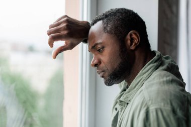 Depresyondan muzdarip, hayal kırıklığına uğramış, yetişkin Afro-Amerikan bir adam ve iç mekandaki pencerenin yanında kötü haberler. Sağlık sorunları, covid-19 karantinası sırasında kendini izole etmenin stresi