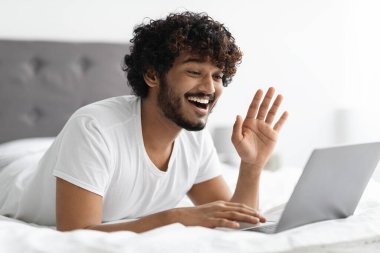 Beyaz pijamalı, mutlu, kıvırcık sakallı, Hindu bir adam. Arkadaşlarıyla internette parti yapıyor. Doğulu neşeli bir adam, dizüstü bilgisayara bakıyor ve el sallıyor.