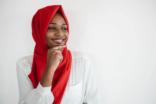 いい提案だ 不思議な黒いイスラム教徒の女性は 自由空間を見て 光の背景にポーズをあごに触れています イスラム教徒の女性は何かを考え遊び心に満ちた笑顔 — ストック写真
