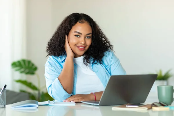現代オフィスの職場で働くオンラインカメラに笑顔ノートパソコンの近くにポーズをとる幸せな黒人実業家 女性のビジネスキャリアとインターネット技術の概念 — ストック写真