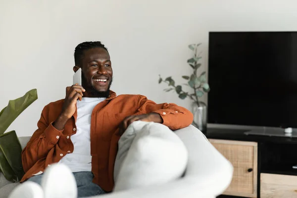 Hombre Negro Feliz Hablando Teléfono Celular Mirando Lado Sentado Sofá — Foto de Stock
