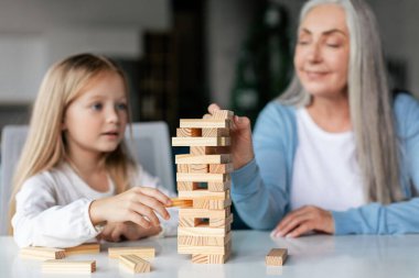 Yaşlı büyükannesi oyun kulesi olan neşeli beyaz bir torun. Oturma odasının içinde masa oyununun keyfini çıkar. Evde aşk ve ilişkiler, aile boş zamanlarında covid-19 sırasında eğlenir.