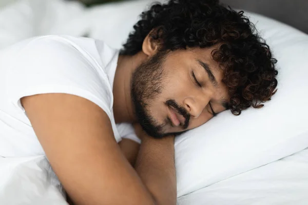 快適なベッドの頭の下で手で彼の側に寝て 自宅で休んでパジャマでハンサムな髭の若いインド人の男の閉鎖 スペースをコピーします 健康な睡眠の概念 — ストック写真
