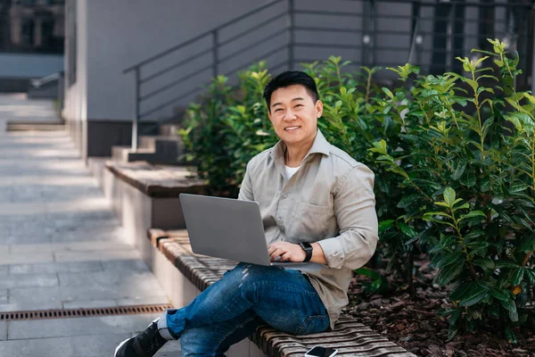 Szczęśliwy Dojrzałe Azji Człowiek Pracuje Laptop Komputer Zewnątrz Siedzi Ławce — Zdjęcie stockowe