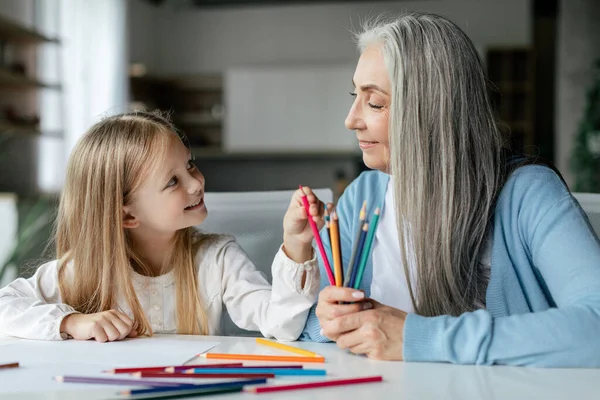 Uśmiechnięta Europejska Wnuczka Starą Babcią Kolorowymi Ołówkami Rysują Stole Obrazek — Zdjęcie stockowe