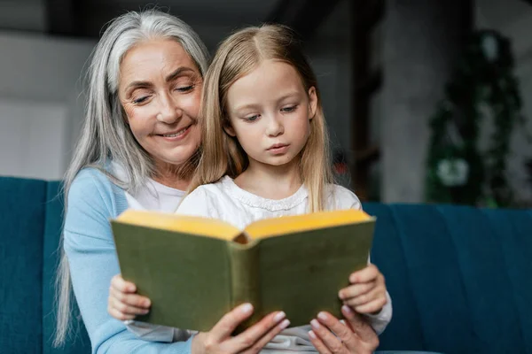 Счастливая Маленькая Кавказская Внучка Старшая Леди Читают Книгу Диване Интерьере — стоковое фото