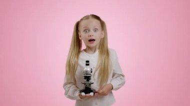 İlginç bir bilim. Mikroskoba bakan meraklı küçük bir kız, bilim adamı ya da doktor gibi oynuyor, deney sonuçlarından zevk alıyor, pembe stüdyo geçmişi, yavaş çekim