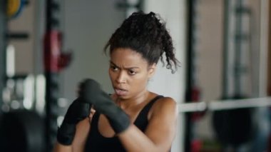 Kadınlar ve güçlü spor. Genç, aktif, Afro-Amerikan kadın kickboks sporunun yakın portresi, bantlara sarılmış yumruklar, yavaş çekim.