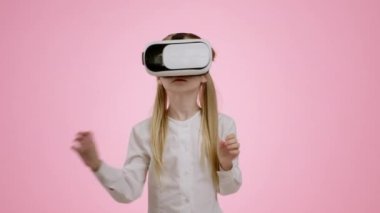 Modern teknoloji ve eğitim. VR gözlük takan küçük şirin bir kızın, artırılmış gerçekliğin tadını çıkarırken, oyun oynarken ya da ders izlerken, pembe arka plan, ağır çekim