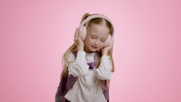 Счастливая Маленькая Школьница Рюкзаком Слушающая Музыку Через Большие Беспроводные Наушники — стоковое видео