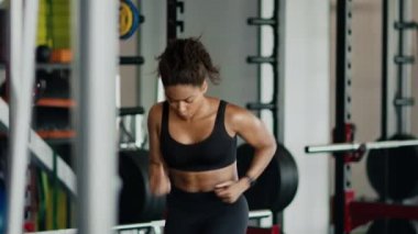 Kardiyo testi. Genç, aktif, Afro-Amerikan kadın sporcu. Hızlı bir şekilde koşuyor ve Smartwatch 'e bakıyor. Spor salonunun tadını çıkarıyor, yavaş çekim, serbest alan.