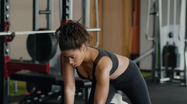 Vücut geliştirme konsepti. Genç, aktif, Afro-Amerikan kadın sporcu. Spor salonunda dambıl pompalıyor. Göğüs kasları üzerinde çalışıyor.