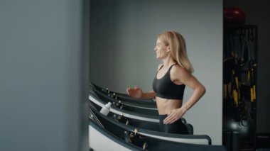 Aktif bir sabah. Koşu bandında koşan mutlu sporcu kadın sporcu, modern spor salonunda kardiyo çalışmasının tadını çıkarıyor, izleme çekimi, yavaş çekim.