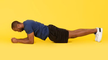 Dirsek Plank Egzersizi yapan Sportif Siyah Adam Sarı Stüdyo Arkaplanı Üzerinde Egzersiz Yapıyor. Sağlıklı Spor ve Vücut Geliştirme Konsepti. Yan Görünüm, Panorama