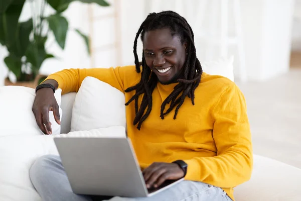 Sonriente Chico Negro Descansando Con Ordenador Portátil Sofá Casa Hombre —  Fotos de Stock